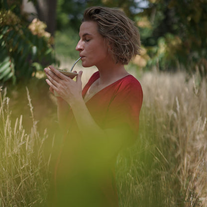 Frau trinkt caámate Bio Mate Tee in der cuia im Feld